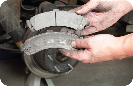 A person is holding a pair of brake pads in their hands.