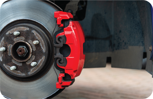 A close up of a red brake caliper on a car wheel.