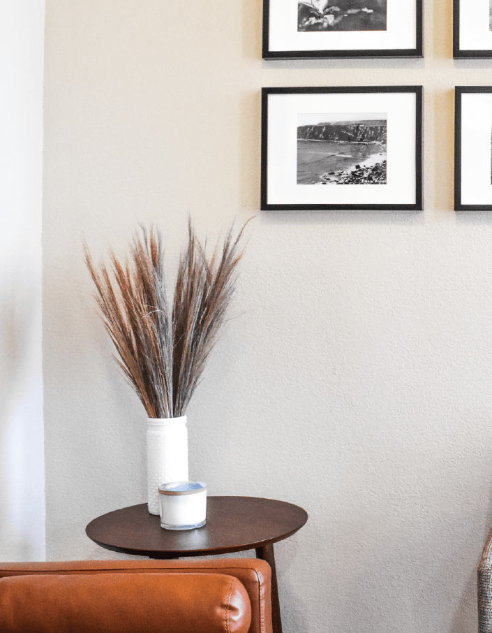 A living room with a couch and a table with a vase of flowers on it.