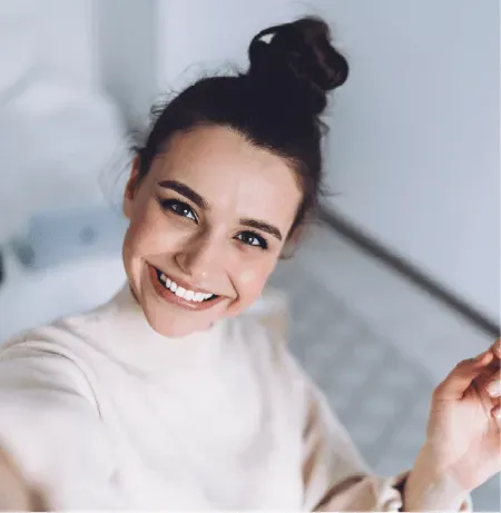 A woman is taking a selfie with her hair in a bun.