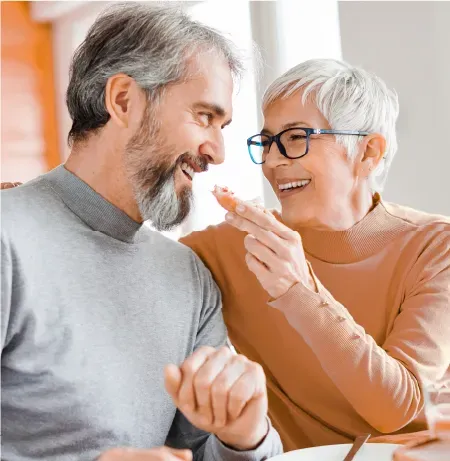 A man and a woman are sitting at a table eating food.