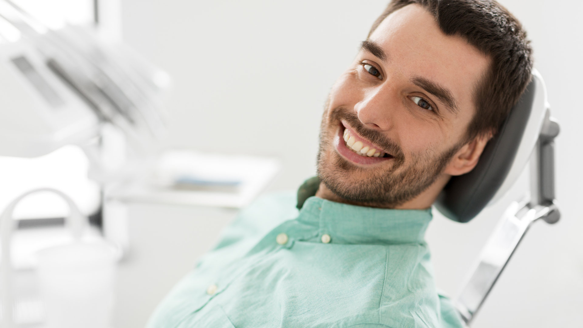 A man is smiling while sitting in a dental chair.
