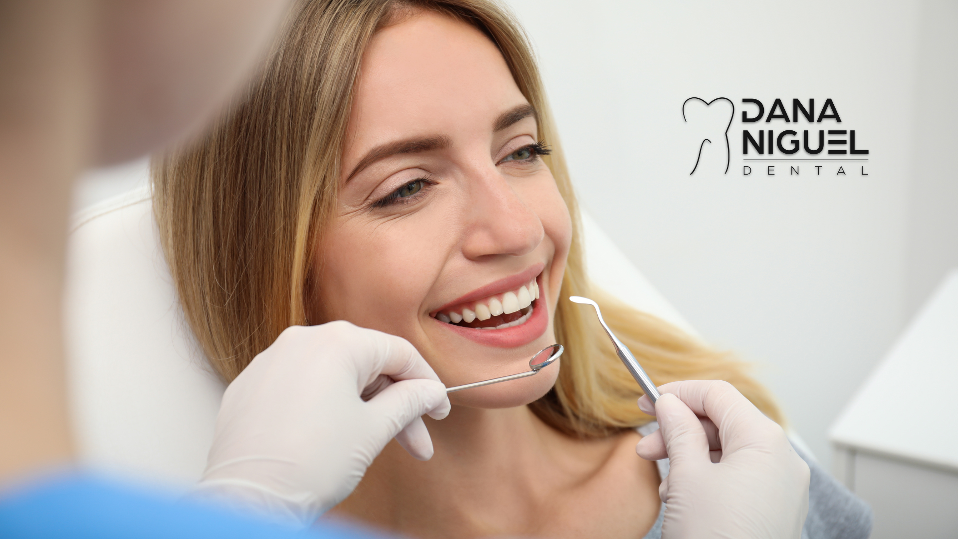 A woman is smiling while having her teeth examined by a dentist.