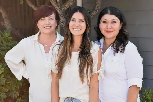 Three women are posing for a picture together in front of a building.