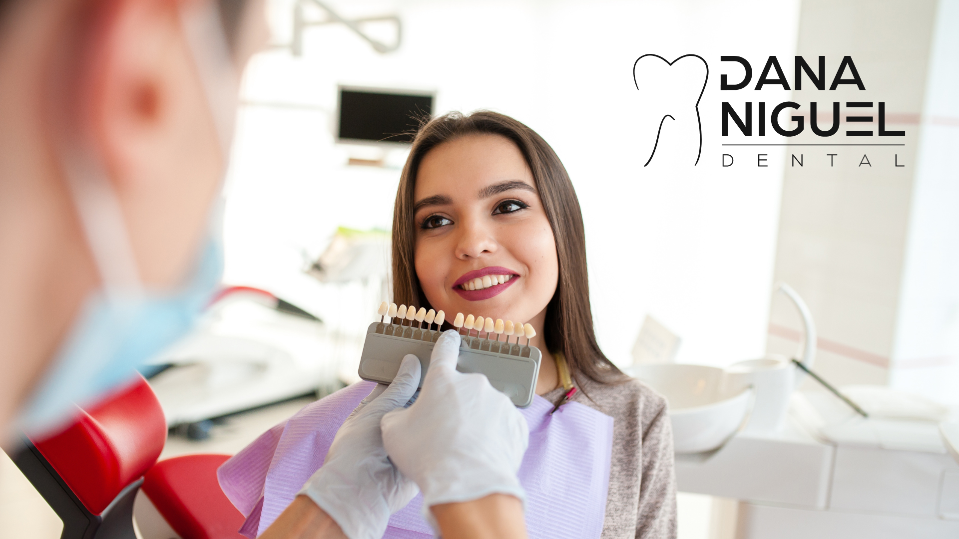 A woman is sitting in a dental chair while a dentist examines her teeth.