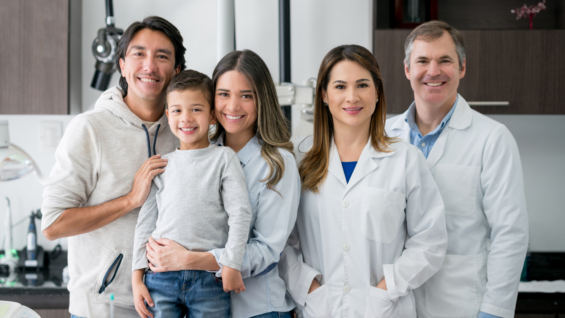 A family and a group of doctors are posing for a picture in a kitchen.