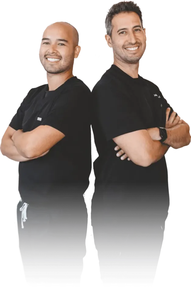 Two men are standing back to back with their arms crossed.