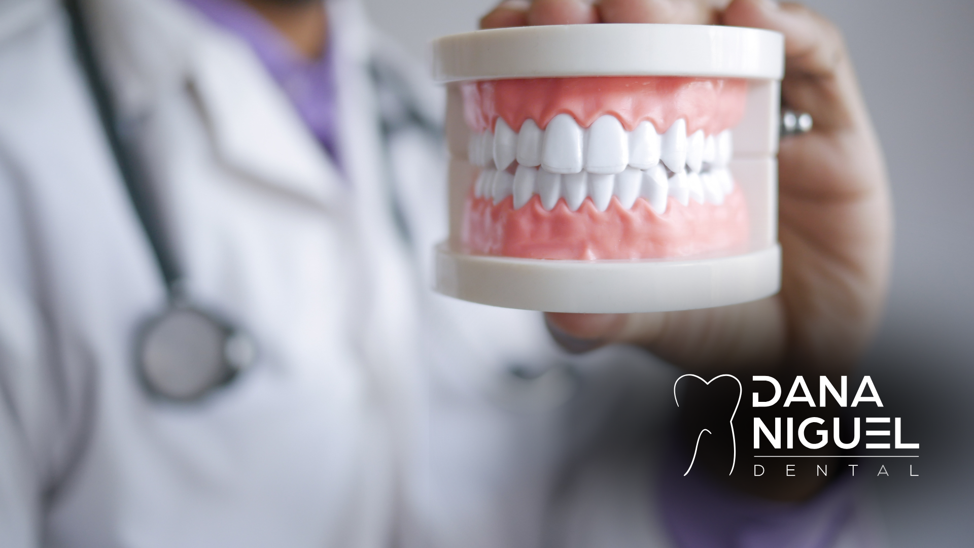 A dentist is holding a model of teeth in his hand