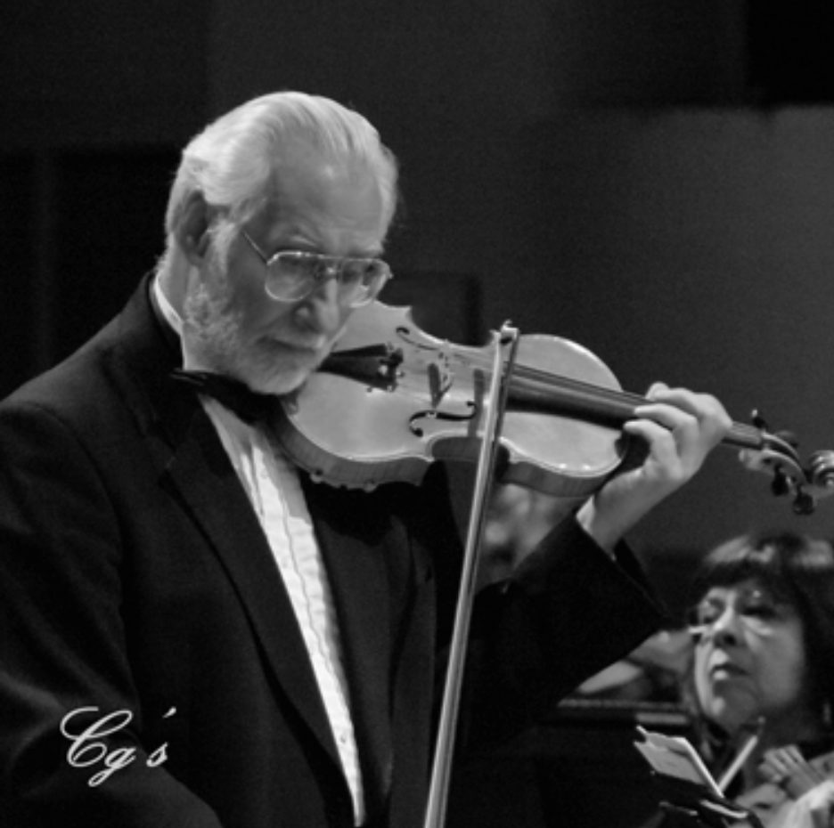 Older man playing violin during concert.