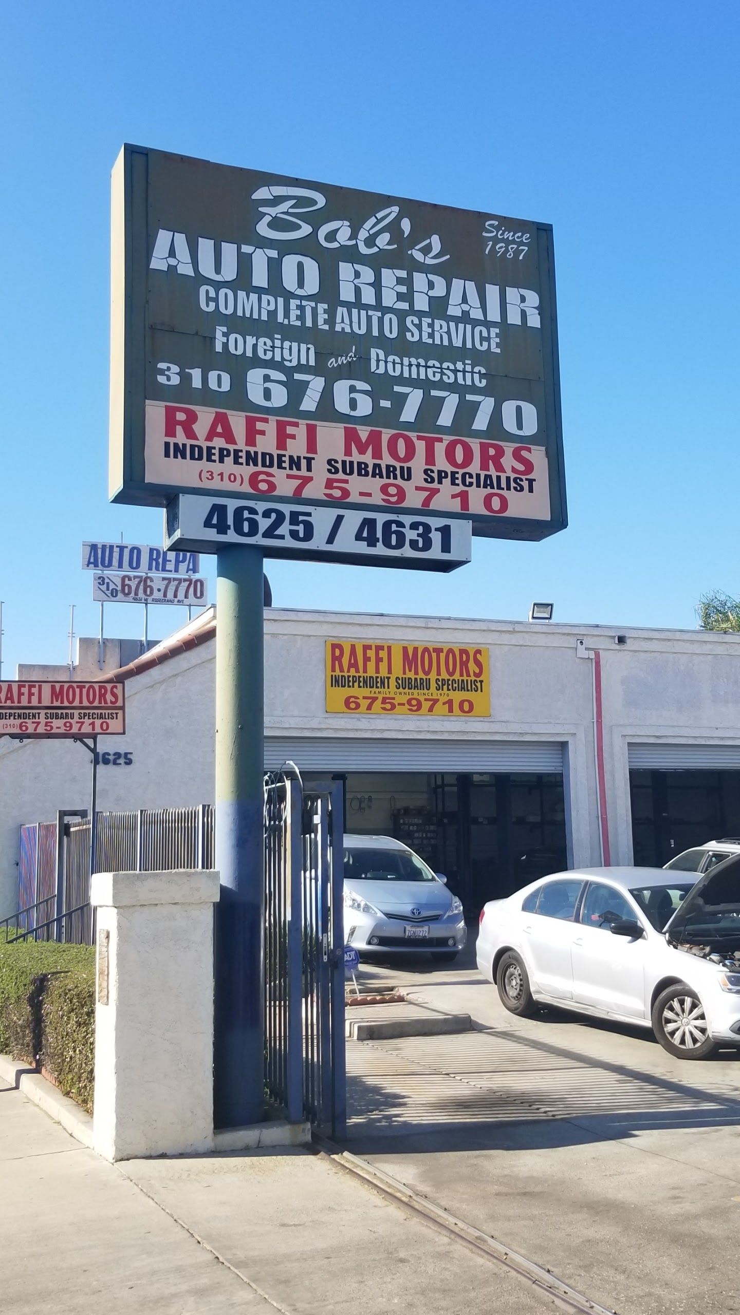 Sign for Zabi's Auto Repair & Raffi Motors. Building with garage doors, cars, and clear blue sky.  | Bob's Auto Repair