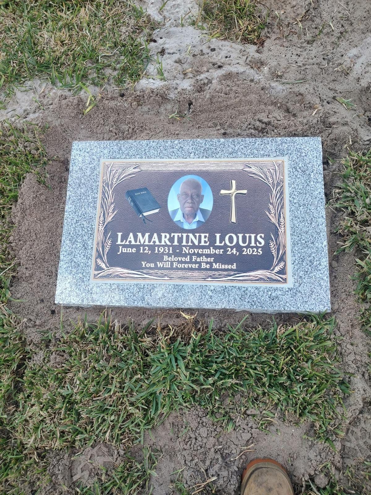 Grave marker for Lamartine Louis, with a photo, cross, and dates on a granite slab, set in grass.