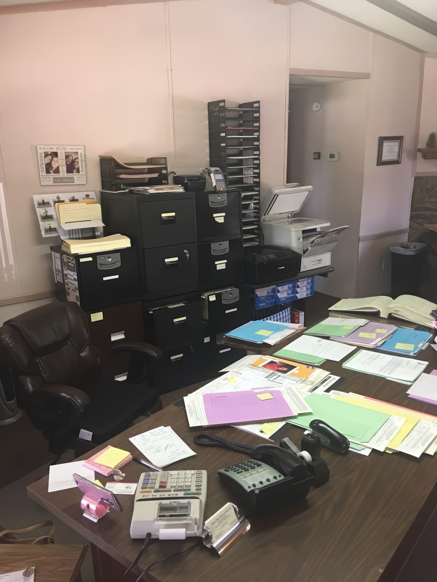 Person working at a wooden desk with a computer, phone, and keyboard.