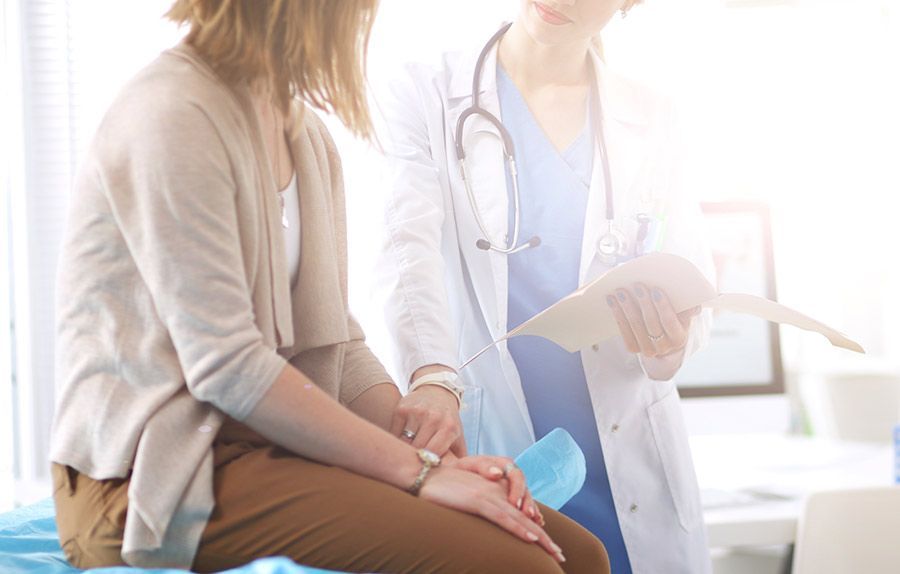 A doctor is talking to a patient who is sitting on a bed.