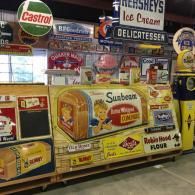 A display of vintage signs, including Sunbeam bread and Hershey’s Ice Cream, inside a shop or warehouse.