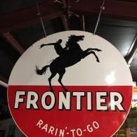 A round, vintage-style sign with a red lower half and white upper half, featuring a black silhouette of a bucking horse.