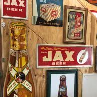 A wall display featuring vintage Jax and High Life beer signs, including a large bottle-shaped sign and framed posters.