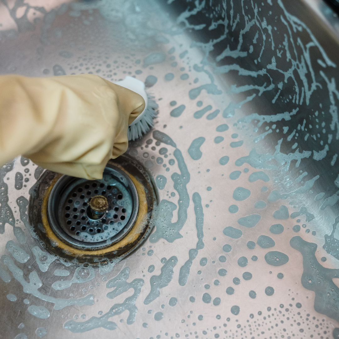 A person is cleaning a sink with a brush