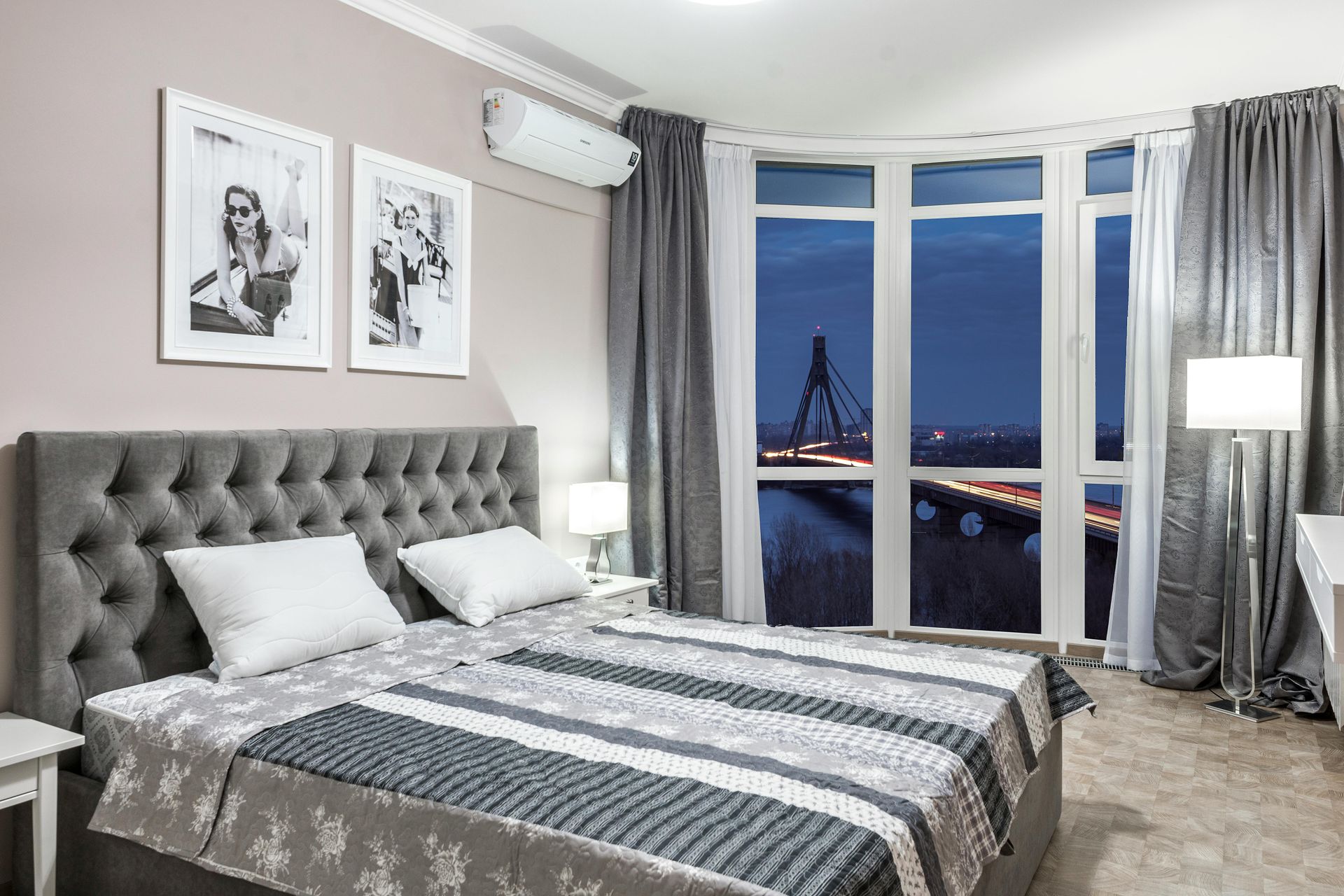 A bedroom with a large bed and a large window with a view of a bridge.