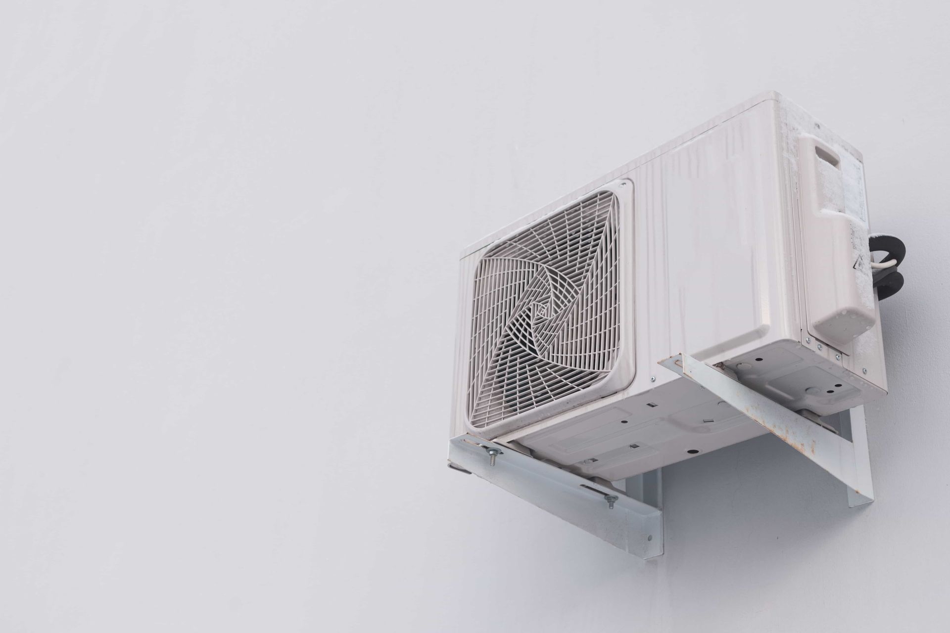 A white air conditioner is mounted on a white wall.