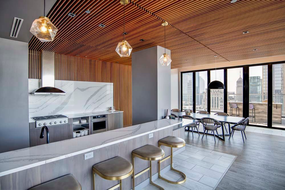 A kitchen with a long counter and stools and a dining room with tables and chairs.