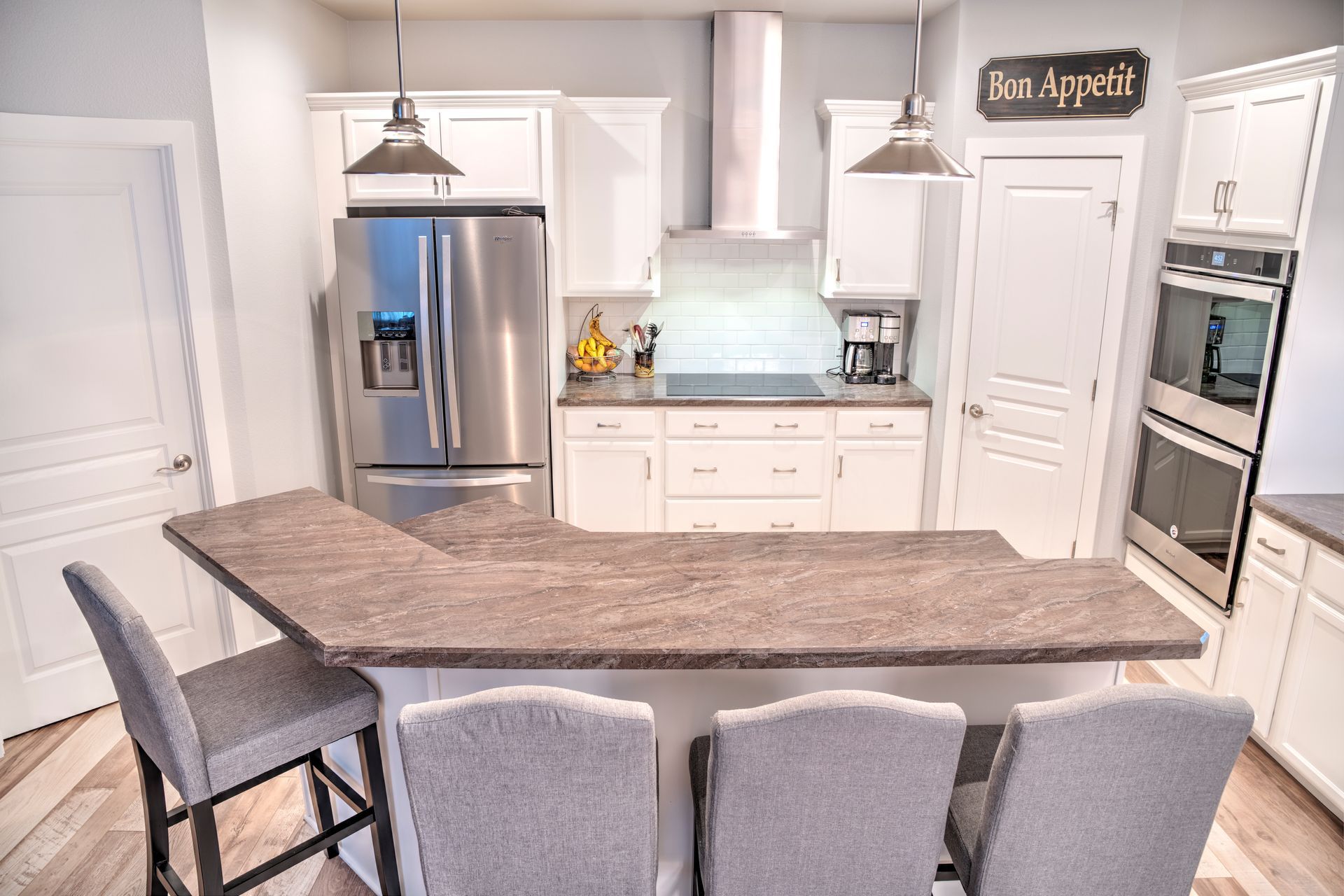 A kitchen with white cabinets and stainless steel appliances and a sign that says appetit