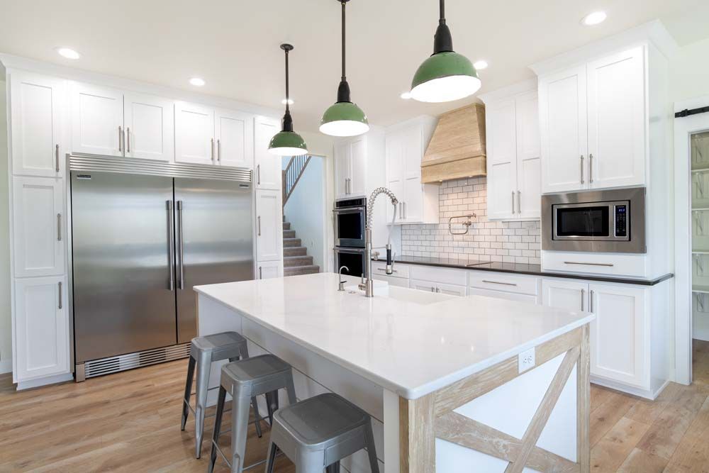 A kitchen with white cabinets , stainless steel appliances , and a large island.