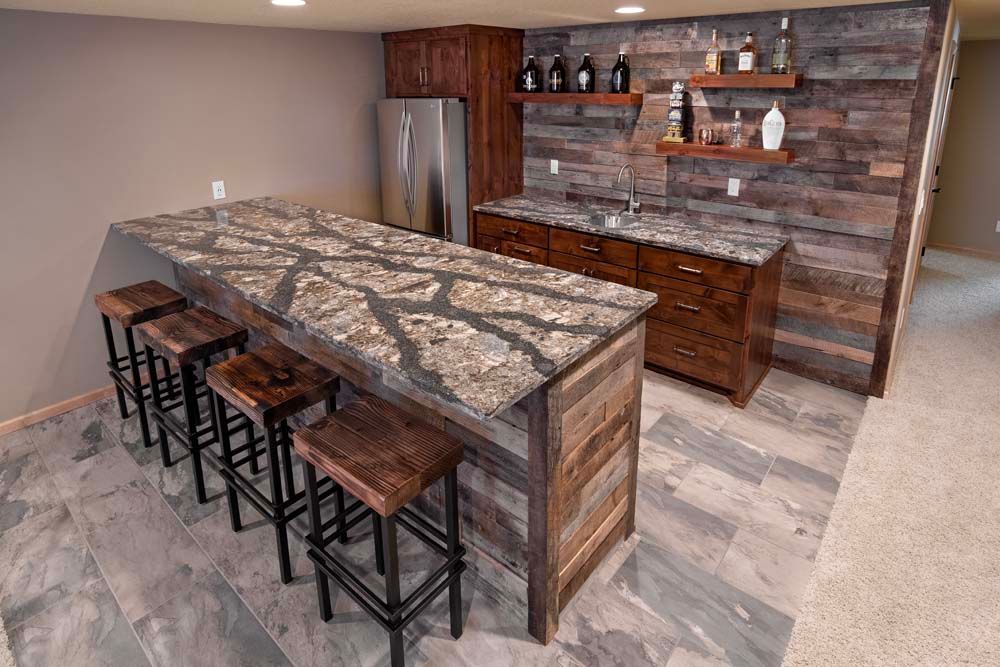 A kitchen with a large island and stools in a basement.