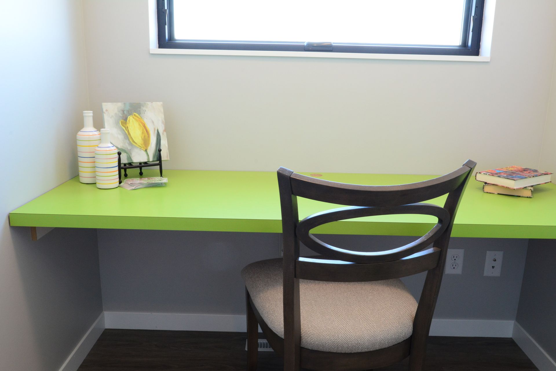 A green desk with a chair in front of a window.