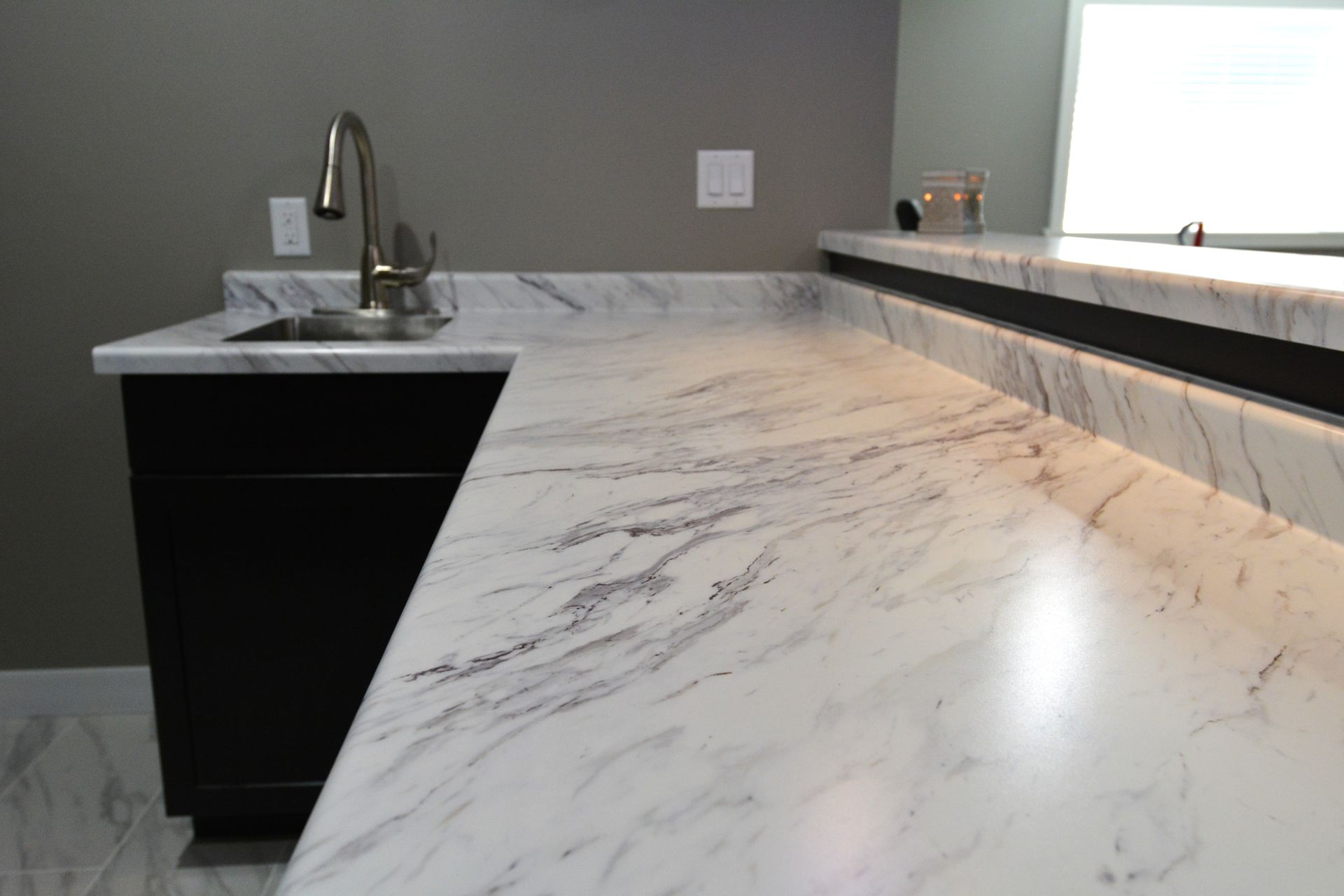 A kitchen with a marble counter top and a sink.