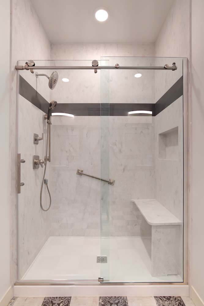 A bathroom with a sliding glass shower door and a bench.