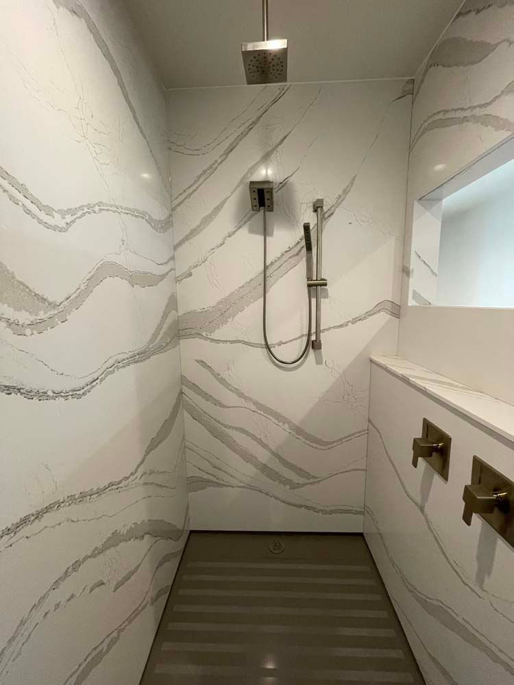 A bathroom with a walk in shower and marble walls.
