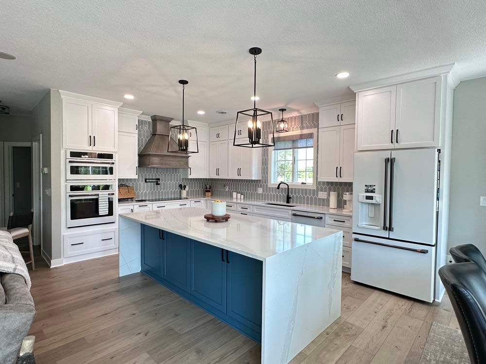 A kitchen with white cabinets and blue cabinets and a large island in the middle.