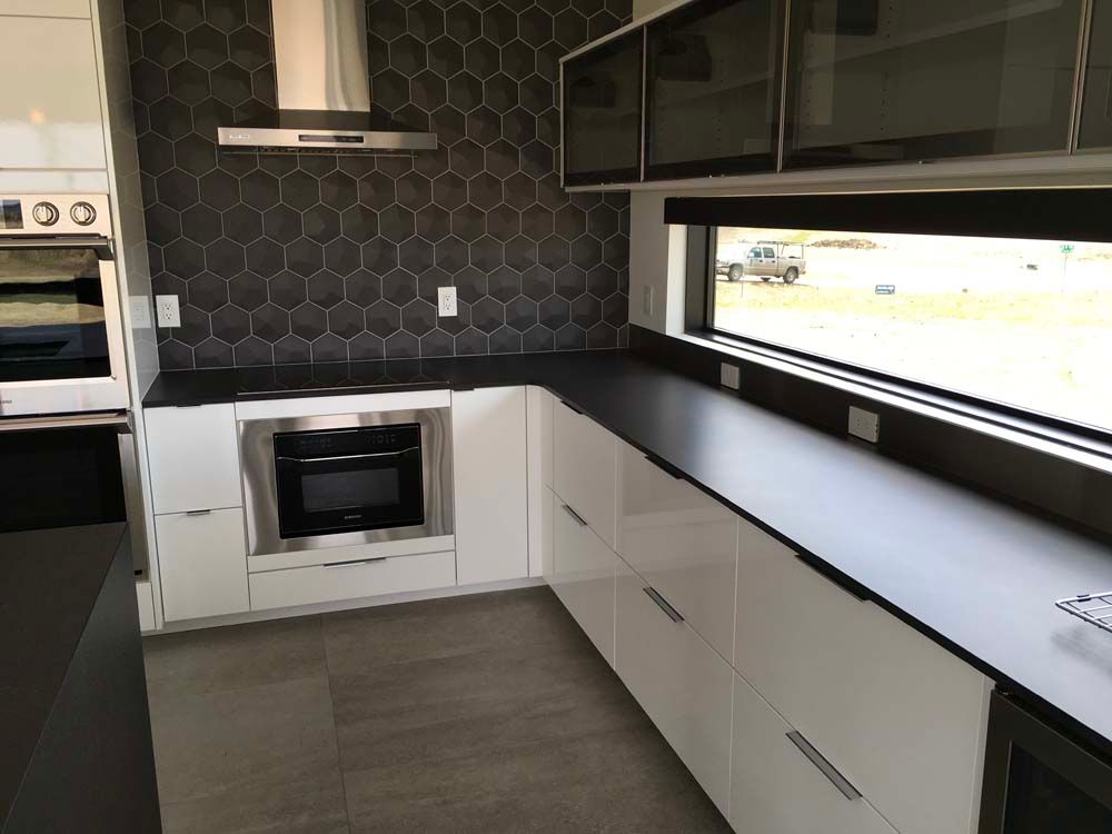 A kitchen with white cabinets and black counter tops