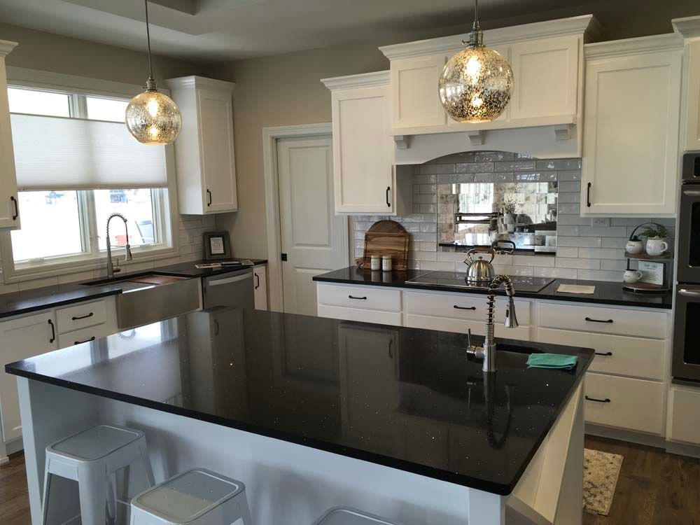 A kitchen with white cabinets and black counter tops