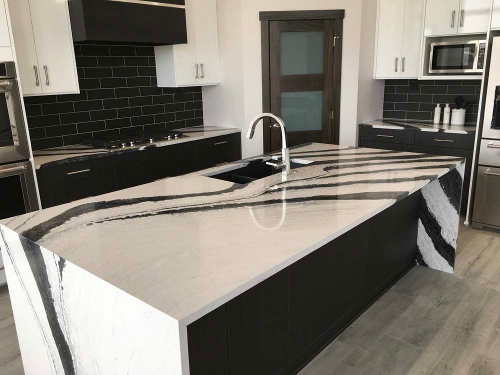 A kitchen with a large island and black and white counter tops