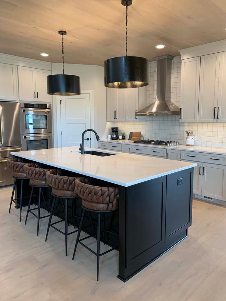 A kitchen with white cabinets and stainless steel appliances and a large island.