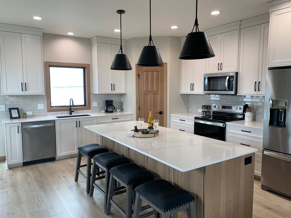 A kitchen with white cabinets , stainless steel appliances , a large island and stools.