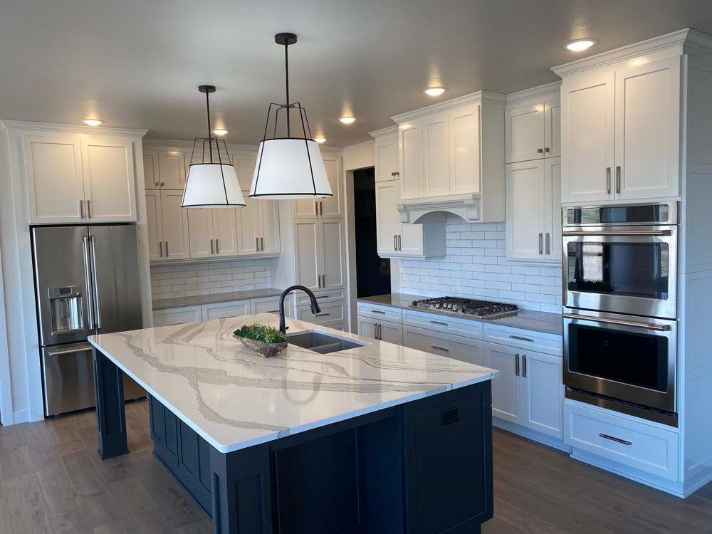 A kitchen with white cabinets , stainless steel appliances , and a large island.