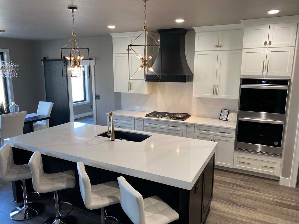 A kitchen with white cabinets and stainless steel appliances and a large island.