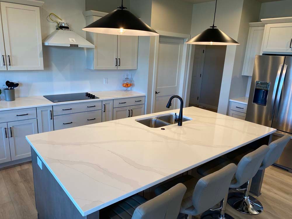 A kitchen with white cabinets , stainless steel appliances , and a large island with a sink.