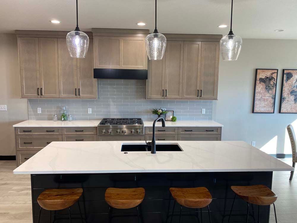 A kitchen with a large island , sink , stove and cabinets.
