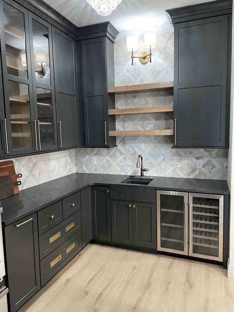 A kitchen with black cabinets , granite counter tops , stainless steel appliances and a wine cooler.