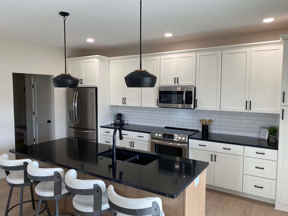 A kitchen with white cabinets , black counter tops , and stainless steel appliances.