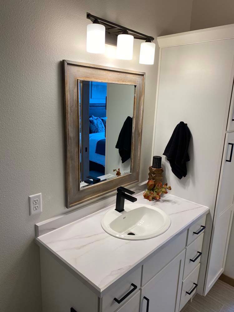 A bathroom with a sink , mirror and light fixture.