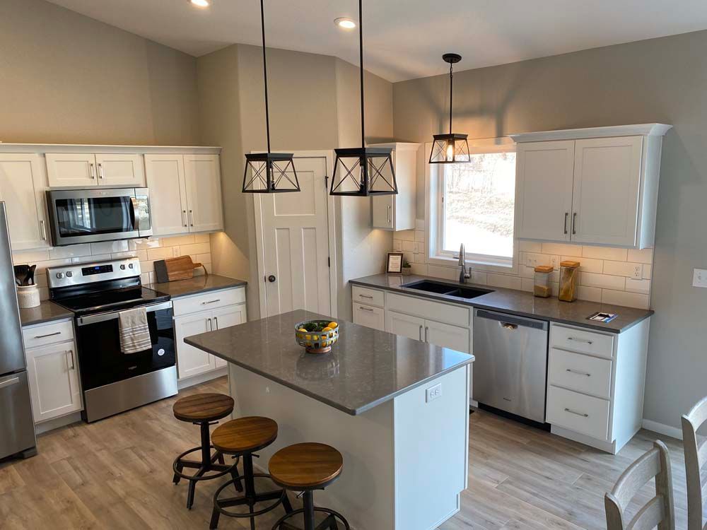 A kitchen with white cabinets , stainless steel appliances , and a large island.