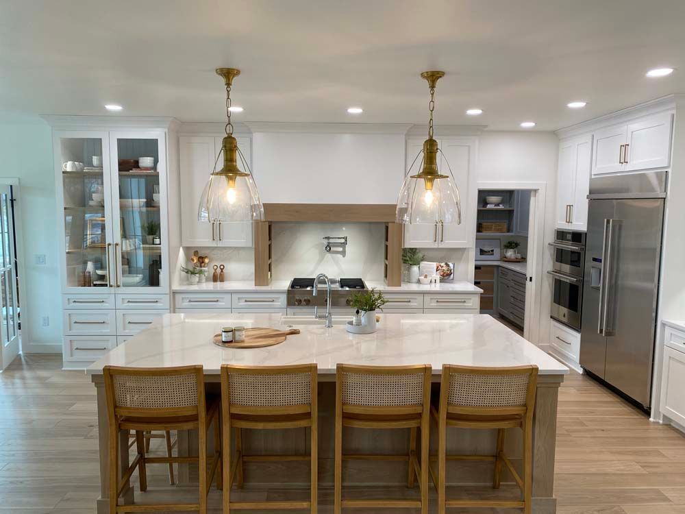 A kitchen with white cabinets , stainless steel appliances , and a large island.