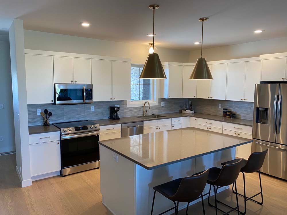 A kitchen with white cabinets , stainless steel appliances , and a large island.