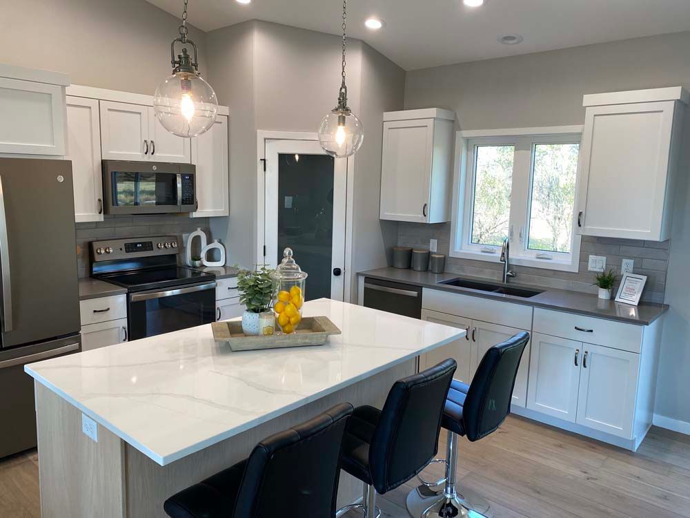 A kitchen with white cabinets , stainless steel appliances , and a large island.