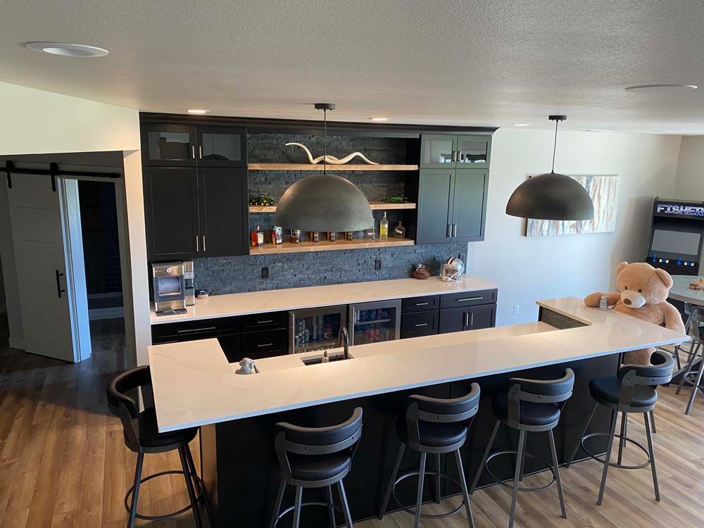 A kitchen with a large island and stools and a teddy bear on the counter.