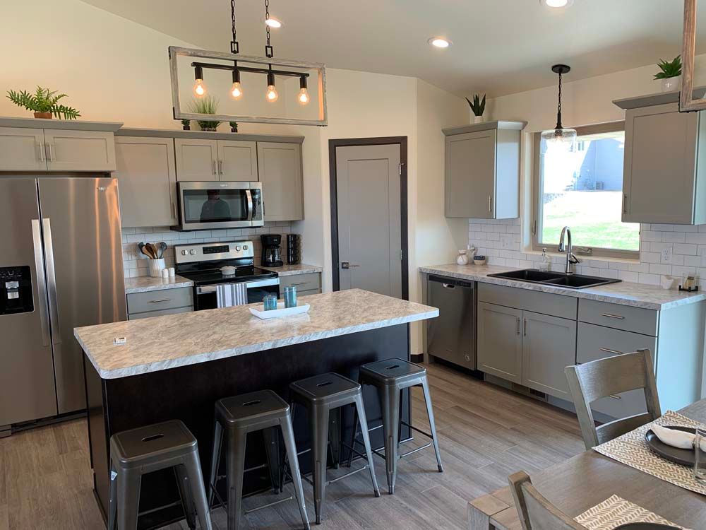 A kitchen with stainless steel appliances and a large island in the middle.